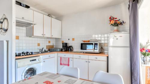 une cuisine avec des armoires blanches et une laveuse et une sécheuse dans l'établissement Les Maldives- B11- Appart lumineux- 6 pers, au Cap d'Agde