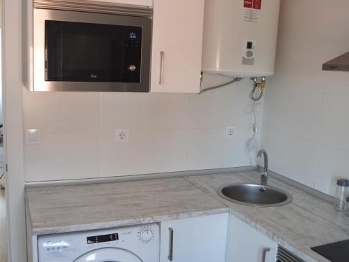 eine kleine Küche mit einer Spüle und einer Mikrowelle in der Unterkunft Nuevo apartamento en Santander! in Santander