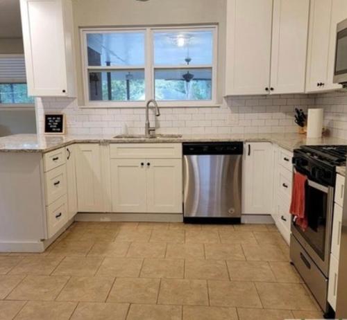 uma cozinha com armários brancos e uma máquina de lavar louça em aço inoxidável em Heyward Long Term Hosts em Savannah