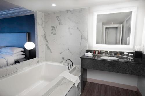 een badkamer met een bad, een wastafel en een bed bij Niagara Falls Marriott on the Falls in Niagara Falls