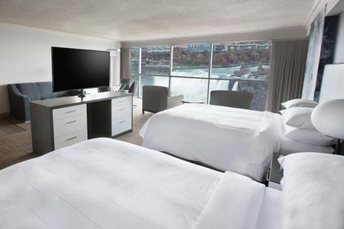 a hotel room with two beds and a flat screen tv at Niagara Falls Marriott on the Falls in Niagara Falls