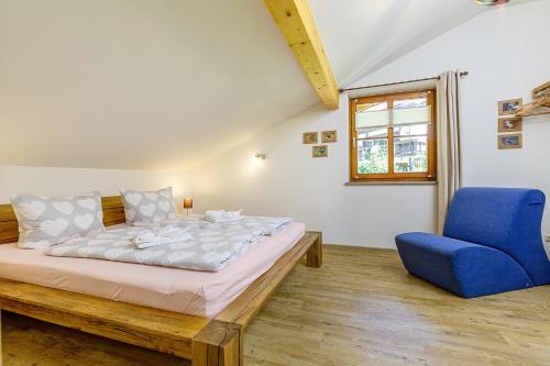 a bedroom with a bed and a blue chair at Ferienhaus Thimlefi in Reit im Winkl