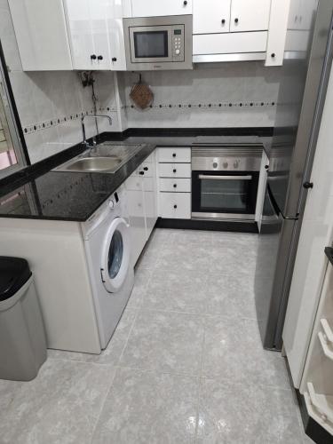 a white kitchen with a sink and a microwave at Casiña de Érika in San Cosme de Barreiros