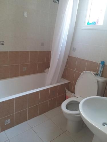 a bathroom with a toilet and a tub and a sink at Tala Gardens Apartment in Tala