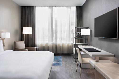 AC Hotel by Marriott Grand Rapids Downtown في غراند رابيدز: غرفة في الفندق بها سرير ومكتب وتلفزيون