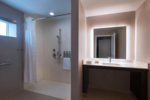 uma casa de banho com um lavatório e um chuveiro com um espelho. em Residence Inn New Brunswick Tower Center Blvd. em East Brunswick