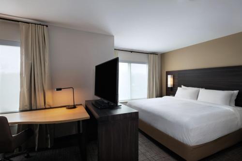a hotel room with a bed and a desk with a television at Residence Inn New Brunswick Tower Center Blvd. in East Brunswick