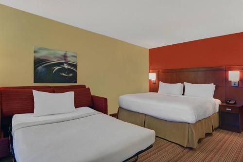 two beds in a hotel room with two bedsskirts at Courtyard Shreveport Airport in Shreveport