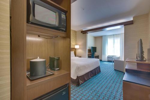 a hotel room with a bed and a flat screen tv at Fairfield Inn & Suites By Marriott Wichita East in Wichita