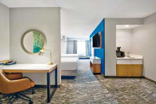 a hotel room with a bed and a desk and a mirror at SpringHill Suites Erie in Erie