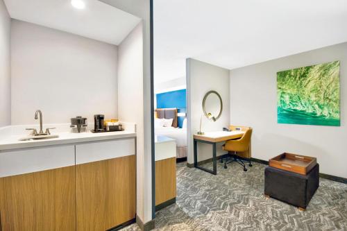 a hotel room with a bathroom with a sink and a desk at SpringHill Suites Erie in Erie