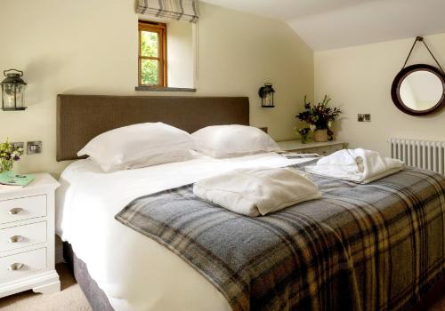 een slaapkamer met een bed met witte lakens en kussens bij Glandwr Cottage at Hendre Rhys Gethin in Betws-y-coed