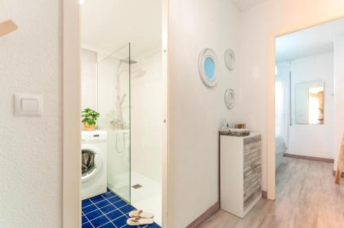 La salle de bains est pourvue d'un lave-linge et d'une porte de douche en verre. dans l'établissement Apartamento con terraza cerca de la playa by InsideHome, à Empuriabrava