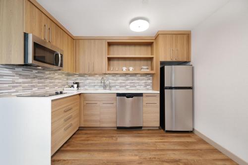 a kitchen with wooden cabinets and a stainless steel refrigerator at Element New York Wood Ridge in Wood-Ridge