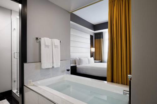 a bathroom with a tub and a bedroom with a bed at Hotel Metro, Autograph Collection in Milwaukee