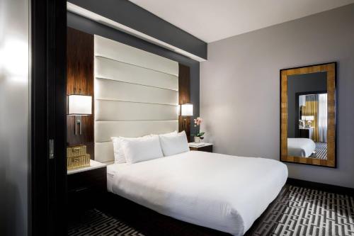 a bedroom with a white bed and a mirror at Hotel Metro, Autograph Collection in Milwaukee