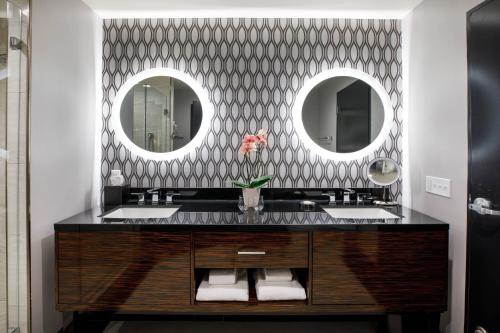 a bathroom with a sink and two mirrors at Hotel Metro, Autograph Collection in Milwaukee