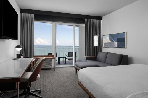 a hotel room with a bed and a desk and a room with a view at Courtyard by Marriott Myrtle Beach Oceanfront in Myrtle Beach