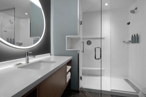 a bathroom with a sink and a shower with a mirror at Courtyard by Marriott Myrtle Beach Oceanfront in Myrtle Beach