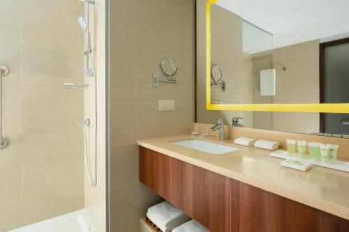 a bathroom with a sink and a shower and a mirror at Courtyard by Marriott Tashkent in Tashkent