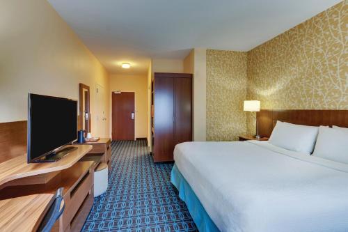 a hotel room with a bed and a flat screen tv at Fairfield Inn & Suites by Marriott Dunn I-95 in Dunn