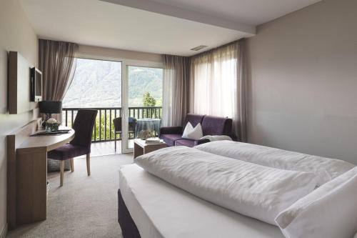 a hotel room with a bed and a balcony at Boutiquehotel Minigolf in Tirolo