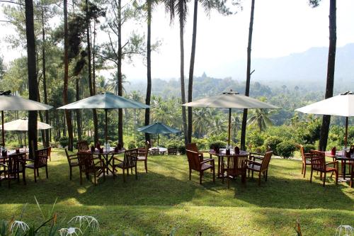 a group of tables and chairs with umbrellas at Manohara Resort in Borobudur