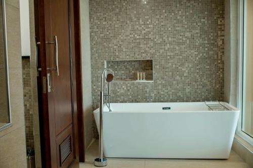 a bath tub in a bathroom with a tile wall at Protea Hotel by Marriott Entebbe in Entebbe