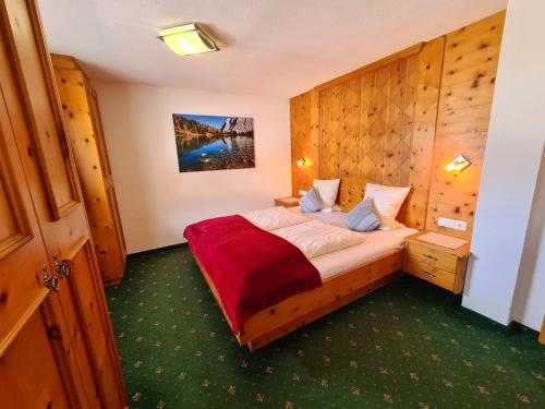 ein Schlafzimmer mit einem Bett mit einer Holzwand in der Unterkunft Appartements Luttinger in Biberwier