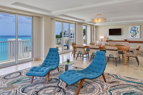 The St. Regis Bermuda Resort في Saint George: غرفة معيشة مع طاولة وكراسي والمحيط