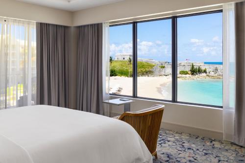 a hotel room with a bed and a view of a beach at The St. Regis Bermuda Resort in Saint George