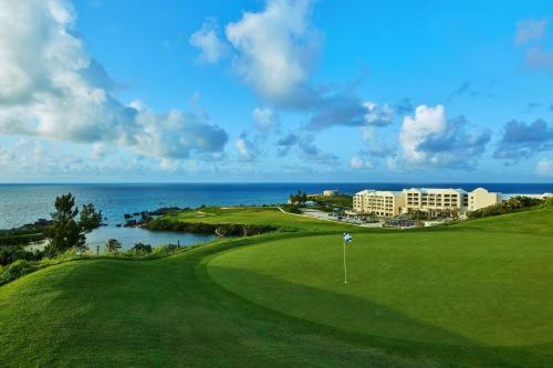 a view of a golf course with a hotel and the ocean at The St. Regis Bermuda Resort in Saint George