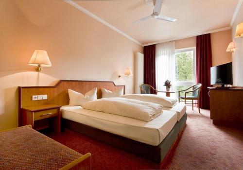 ein Hotelzimmer mit einem großen Bett und einem TV in der Unterkunft Hotel Victoria in Bad Kreuznach