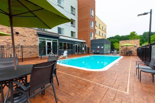 a swimming pool with a table and chairs and an umbrella at Fairfield Inn & Suites by Marriott Atlanta Woodstock in Woodstock