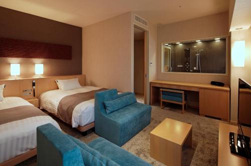 沼津市にあるココチホテル沼津のベッドとソファ付きのホテルルーム