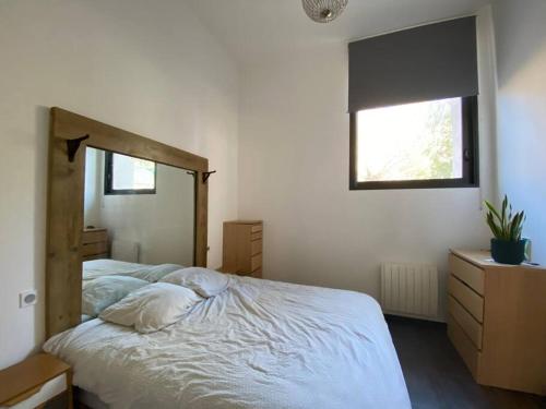 1 dormitorio con 1 cama con sábanas blancas y ventana en Maison 3 chambres cour/bassin, en Pernes-les-Fontaines