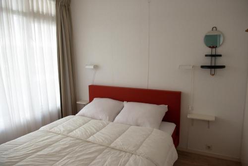 een bed met een rood hoofdeinde in een slaapkamer bij Duinstraatje 51 in Zoutelande