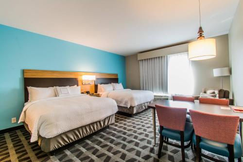 NewburghにあるTownePlace Suites by Marriott Evansville Newburghのベッド2台、テーブルと椅子が備わるホテルルームです。