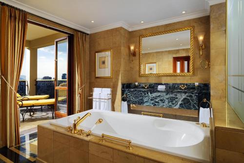 ein Badezimmer mit einer Badewanne und einem großen Spiegel in der Unterkunft Sheraton Addis, a Luxury Collection Hotel, Addis Ababa in Addis Abeba