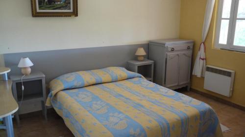 - une chambre dotée d'un lit avec une couverture bleue et jaune dans l'établissement Gite au milieu des vignes g43, à Vidauban