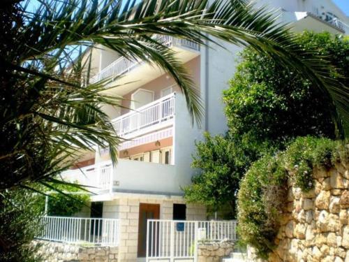 un bâtiment blanc avec un palmier en face dans l'établissement Apartments Ana Hvar, à Hvar