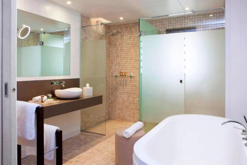 a bathroom with a tub and a sink and a shower at Sheraton New Caledonia Deva Spa & Golf Resort in Bourail