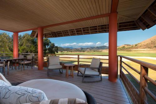 a porch with chairs and tables and a view at Sheraton New Caledonia Deva Spa & Golf Resort in Bourail
