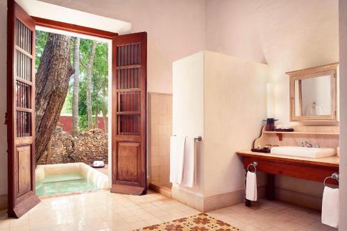 a bathroom with a tub and a sink and a mirror at Hacienda Temozon in Abalá