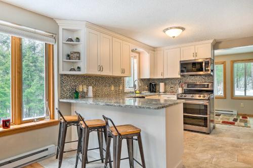 a kitchen with white cabinets and bar stools at Campton Home with Mountain Views Near Trails and Lake in Campton
