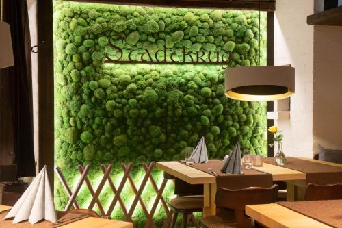 a green wall in a restaurant with two tables at Hotel Stadtkrug in Weiden