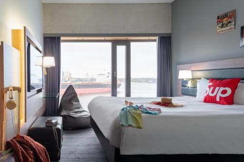 um quarto de hotel com uma cama grande e uma janela grande em Moxy Amsterdam Houthavens em Amsterdã