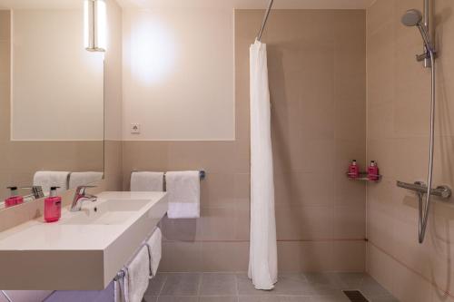 een badkamer met een witte wastafel en een douche bij Moxy Amsterdam Houthavens in Amsterdam