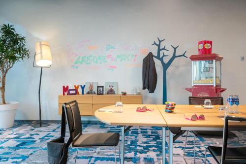 a room with a table with chairs and a tree painted on the wall at Moxy Amsterdam Houthavens in Amsterdam