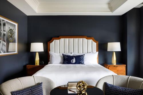 a bedroom with a bed with blue walls and two chairs at The National, Autograph Collection in Oklahoma City